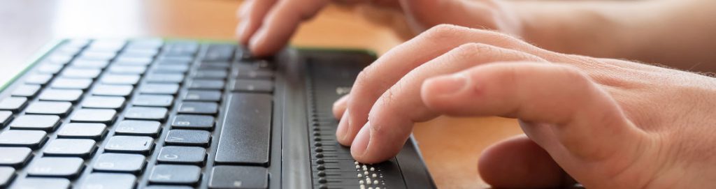A blind man uses a computer with a Braille